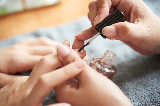 爪にマニキュアを塗っている